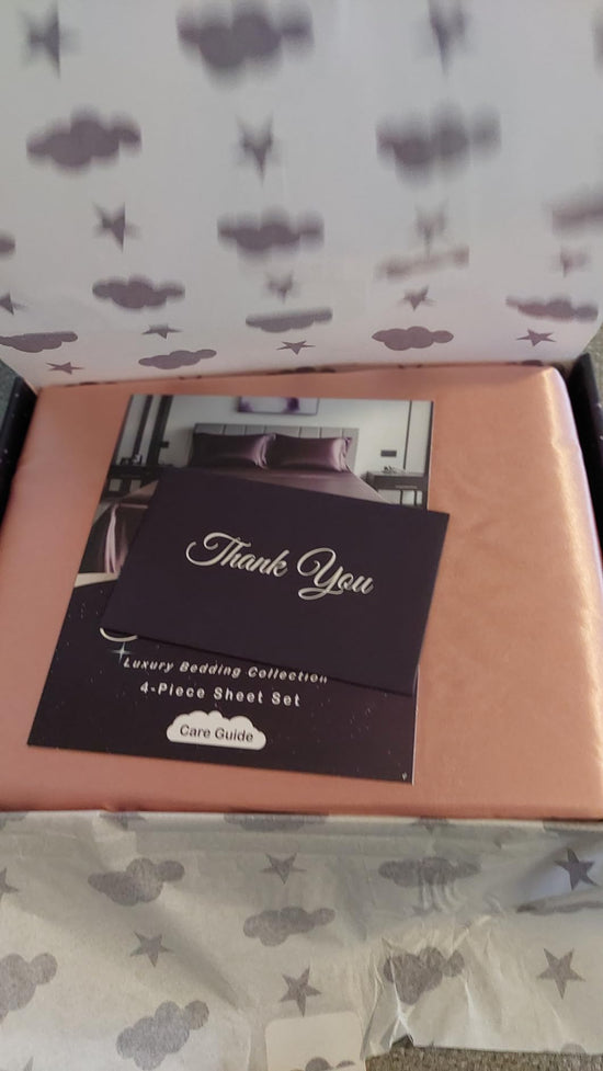Peach satin sheets in an open cloud and star patterned box with a Thank You card and care guide.