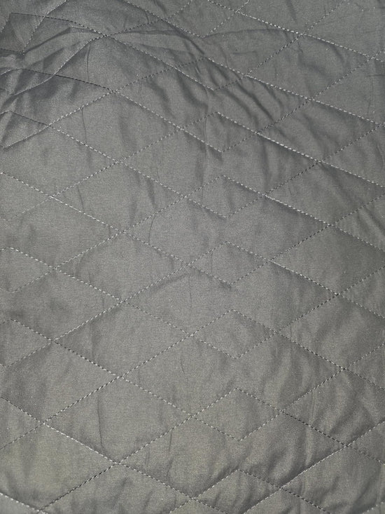 Close-up photograph of gray quilt fabric showing intersecting diamond stitching.