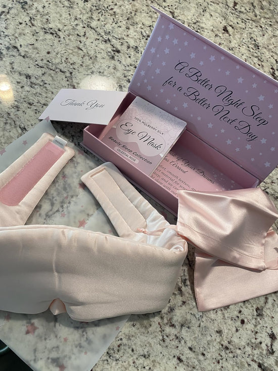 Unboxed pale sleep mask, fabric pouch, care leaflet and Thank You card beside an open lavender presentation box.