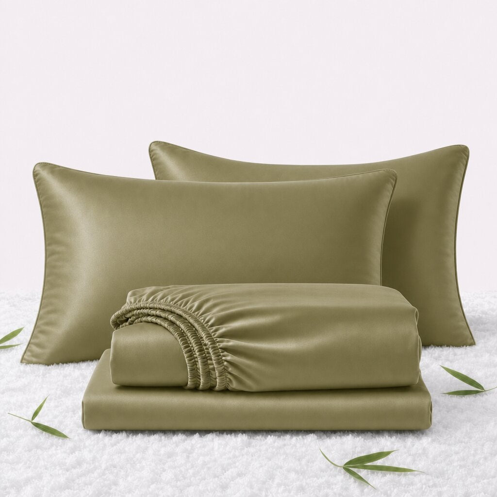Folded olive green sheets in front of 2 matching pillows on a white textured surface with scattered bamboo leaves.