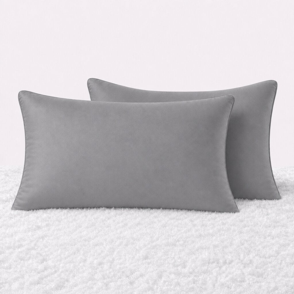 Two pillows in dark gray pillowcases arranged upright on a white textured surface.