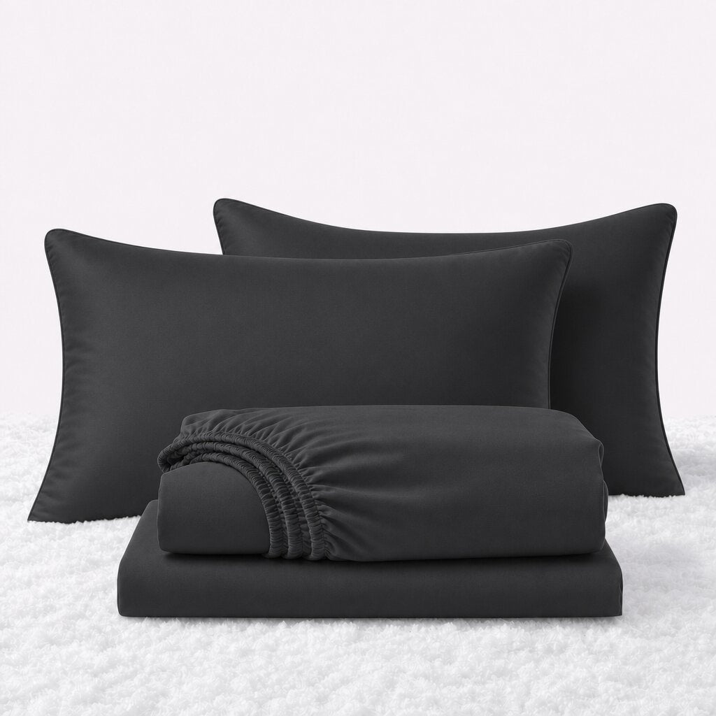 Black sheet set displayed with two pillows behind a folded fitted sheet and flat sheet on a white textured surface.