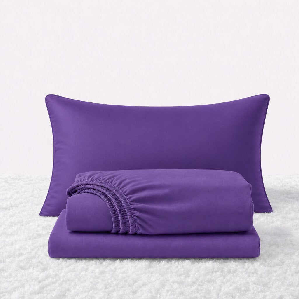 Purple sheet set displayed with one pillow behind a folded fitted sheet and flat sheet on a white textured surface.