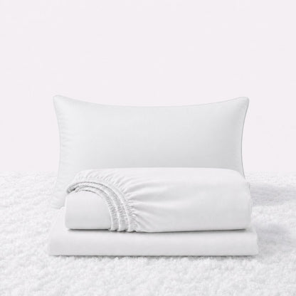 White sheet set displayed with one pillow behind a folded fitted sheet and flat sheet on a white textured surface.