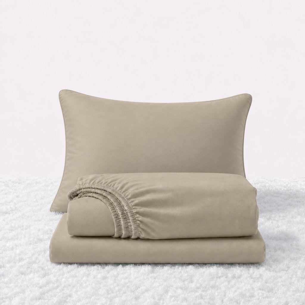 Cream sheet set displayed with one pillow behind a folded fitted sheet and flat sheet on a white textured surface.