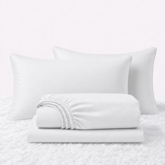 White sheet set displayed with two pillows behind a folded fitted sheet and flat sheet on a white textured surface.