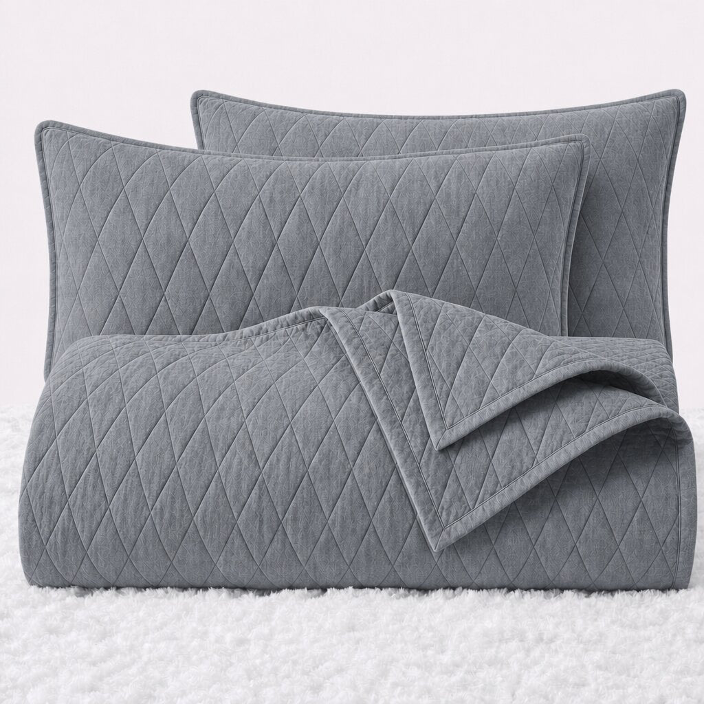 Folded light gray diamond quilted cover with two matching pillow shams on a white textured surface.
