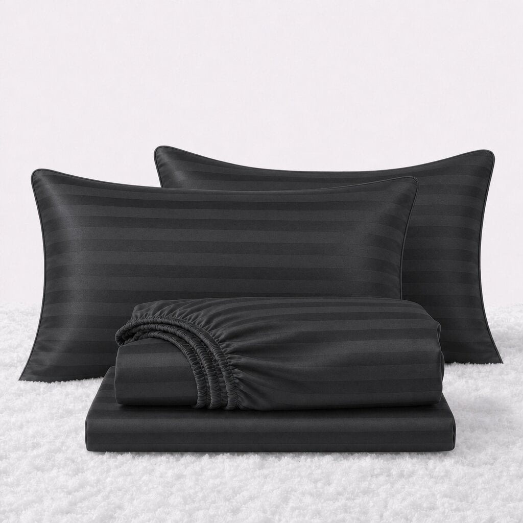 Folded shiny black striped satin sheets in front of two matching pillows on a white textured surface.