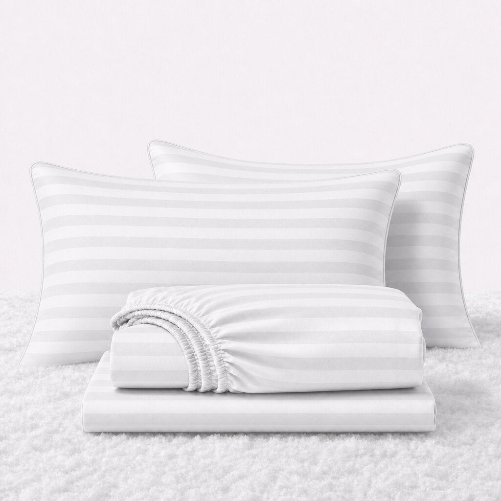 Folded shiny white striped satin sheets in front of two matching pillows on a white textured surface.