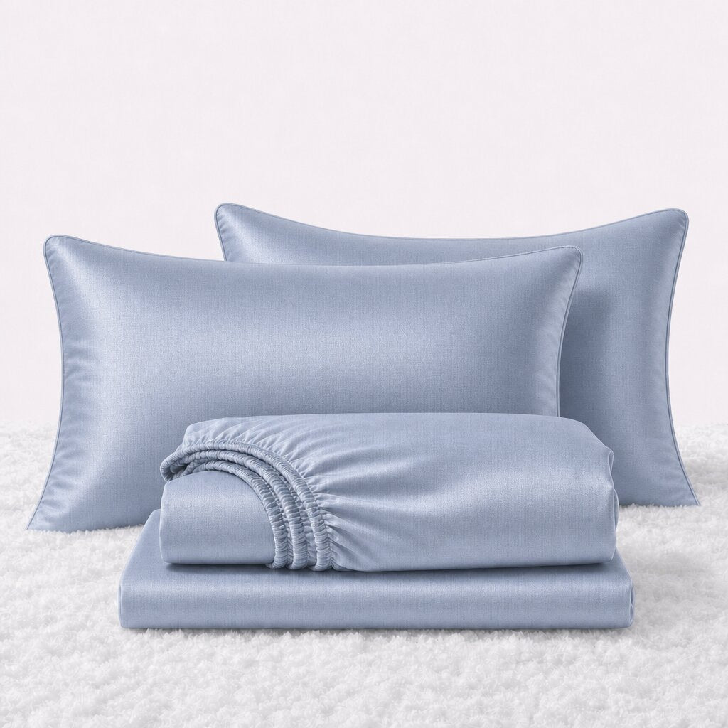 Folded shiny light blue satin sheets in front of two matching pillows on a white textured surface.