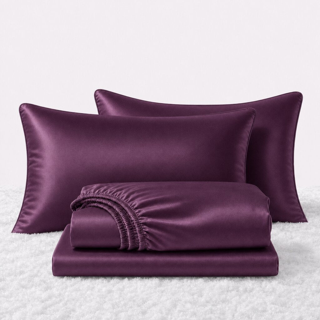 Folded shiny plum satin sheets in front of two matching pillows on a white textured surface.