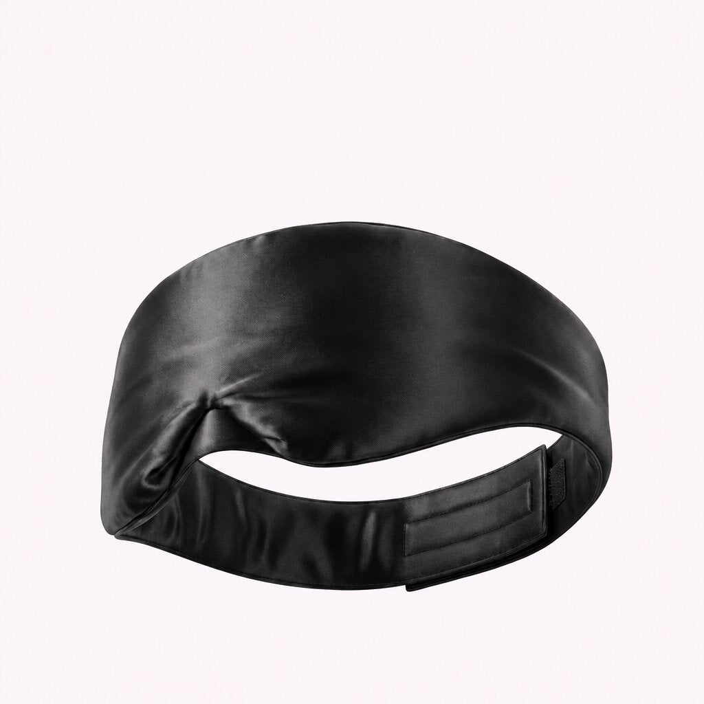 Black sleep mask viewed from the back, showing its wide adjustable fastening strap.