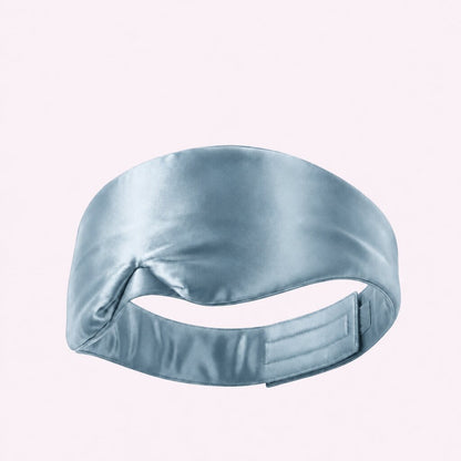 Pale blue wide sleep mask viewed from behind, showing its adjustable fastening strap on a pale background.