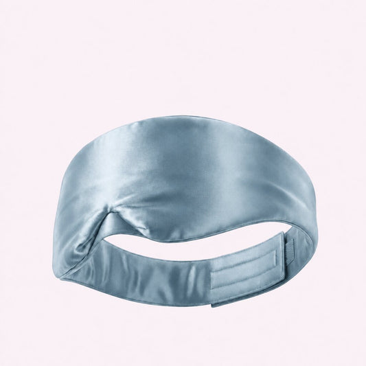 Pale blue wide sleep mask viewed from behind, showing its adjustable fastening strap on a pale background.