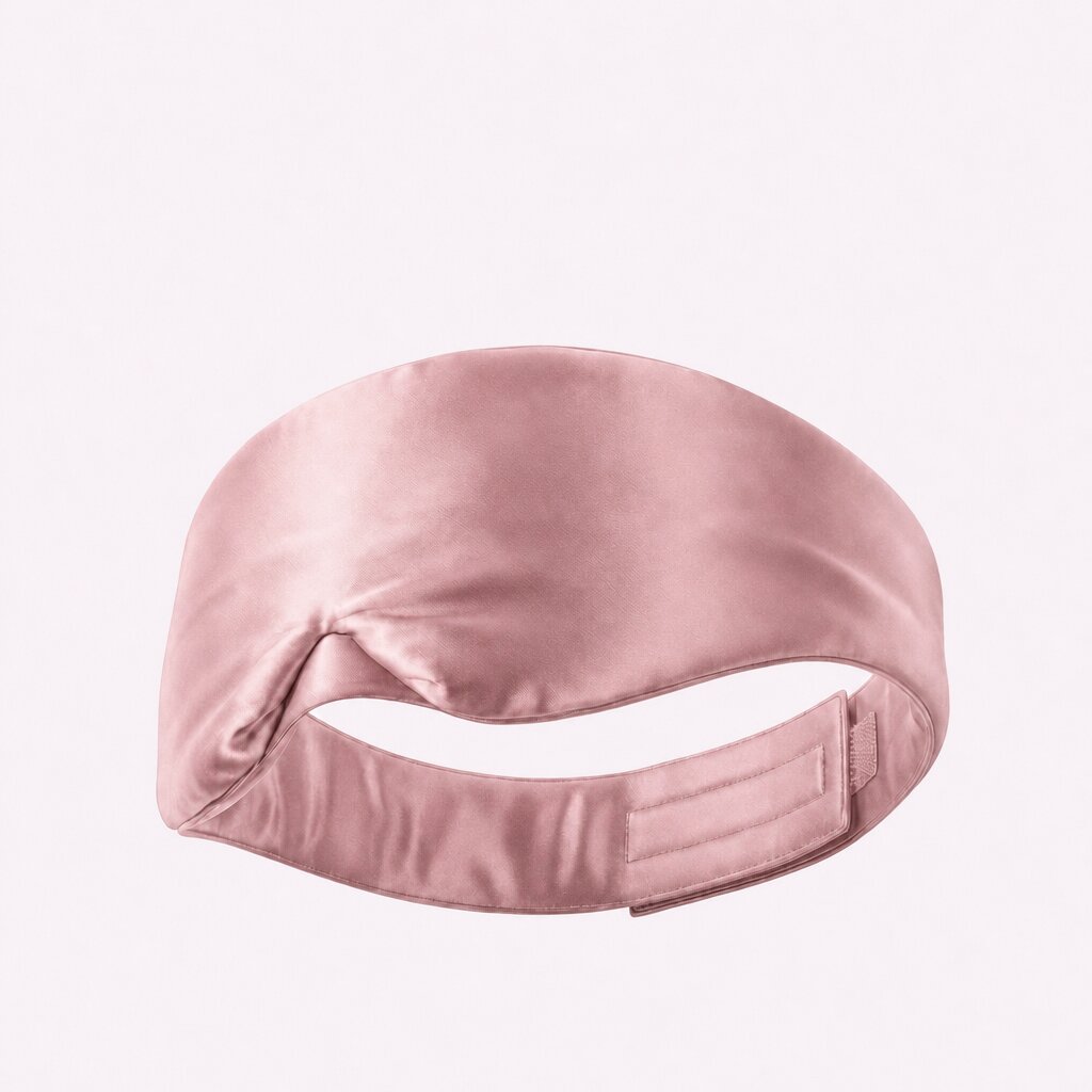 Pink wide sleep mask viewed from behind, showing its adjustable fastening strap on a pale background.