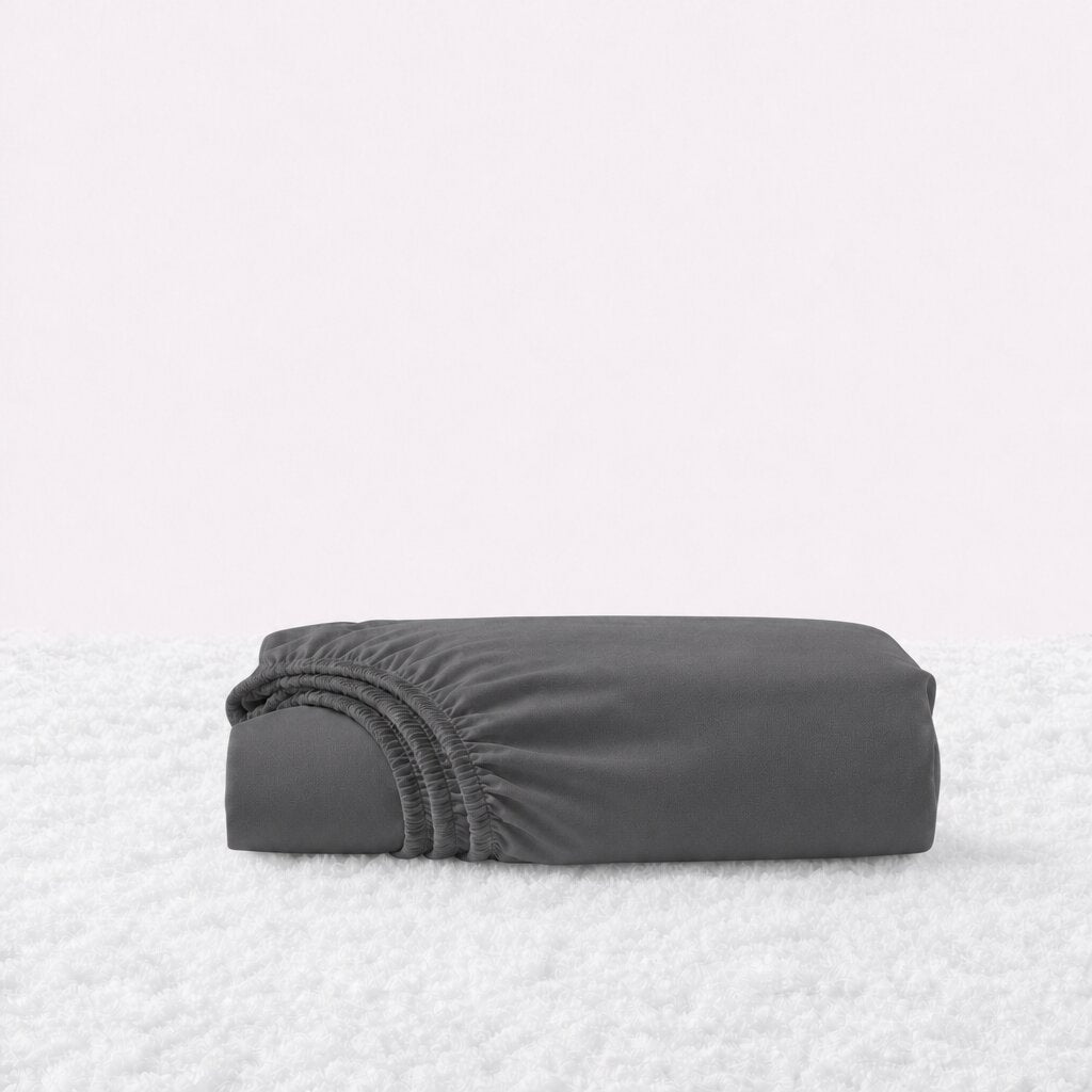 Folded black fitted sheet with its gathered elastic edge visible on a white textured surface.