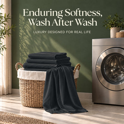 Folded black sheets on a wicker basket beside a washing machine, with the words "Enduring Softness, Wash After Wash".