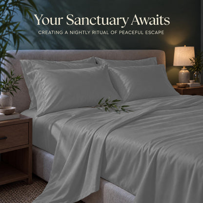 Light gray sheets and matching pillows on a bed beside a lamp, beneath the heading "Your Sanctuary Awaits".