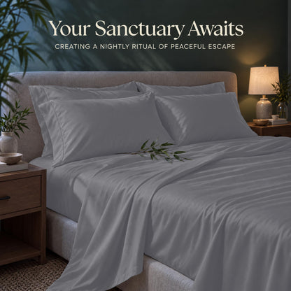 Silver gray sheets and matching pillows on a bed beside a lamp, beneath the heading "Your Sanctuary Awaits".