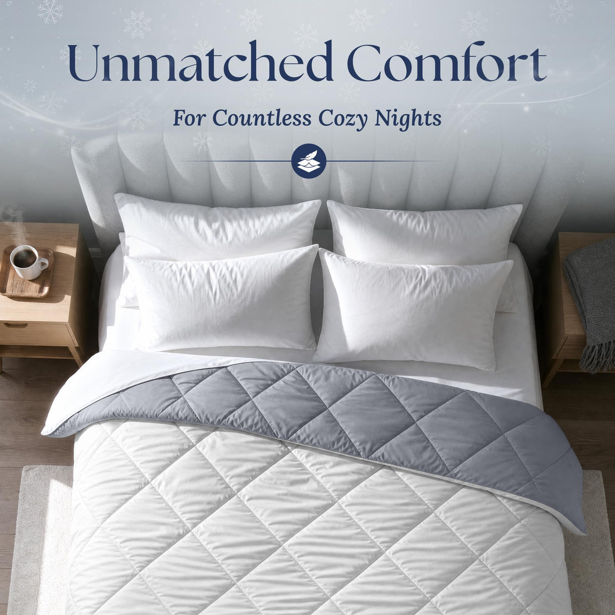 Overhead view of a light gray diamond quilted comforter folded back to show its dark gray reverse, with four white pillows.