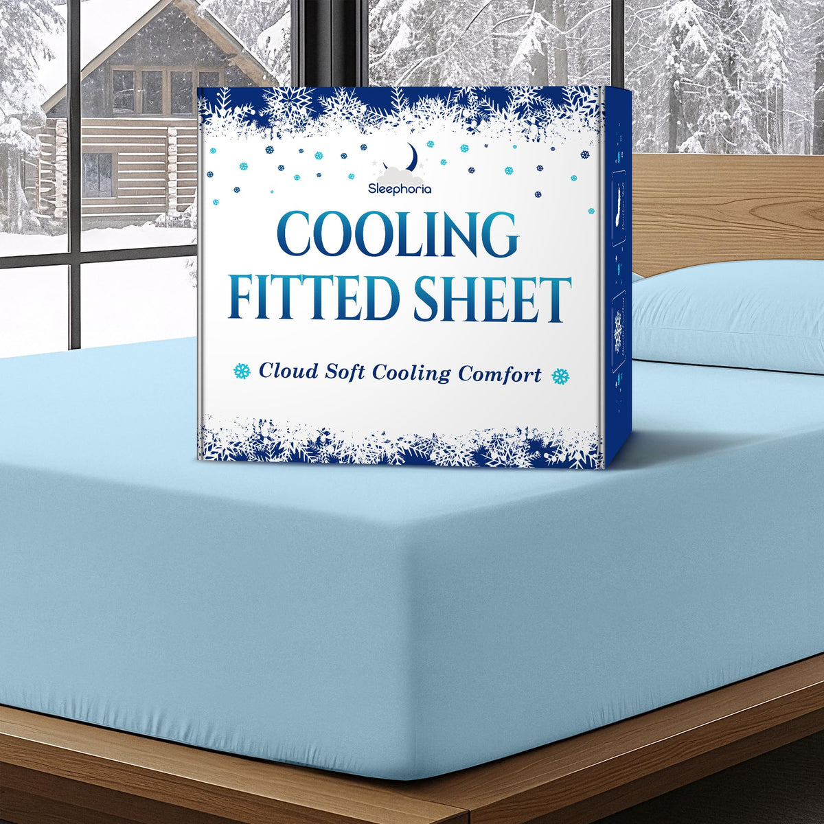 Sleephoria Cooling Fitted Sheet box standing on a light blue fitted sheet, with matching pillows and snowy trees outside.