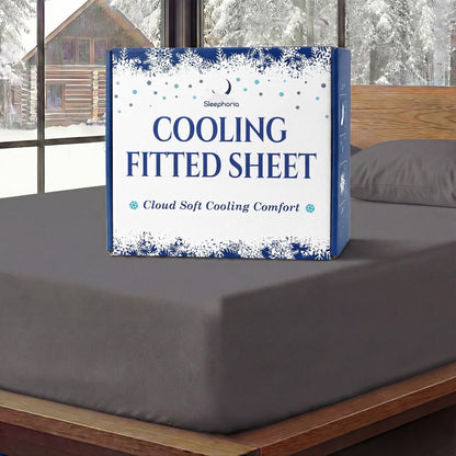 Sleephoria Cooling Fitted Sheet box standing on a charcoal gray fitted sheet, with matching pillows and snowy trees outside.