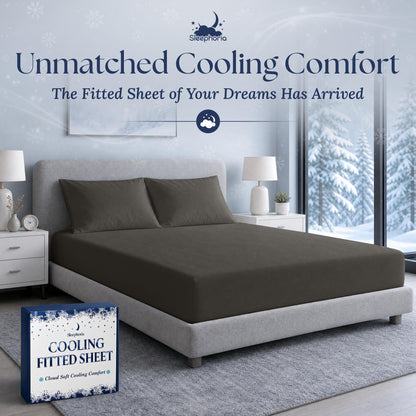 Charcoal gray fitted sheet pulled over a mattress with two matching pillows on a gray bed, beside Sleephoria packaging.