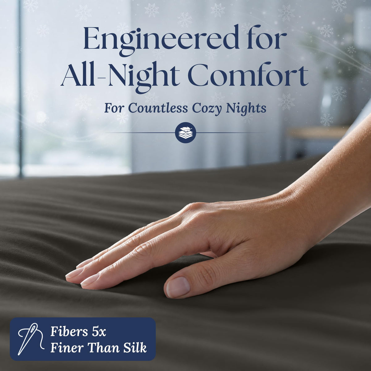 A hand smoothing a charcoal gray fitted sheet. The graphic reads "Fibers 5x Finer Than Silk".