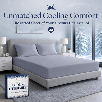 Pale blue gray fitted sheet pulled over a mattress with two matching pillows on a gray bed, beside Sleephoria packaging.