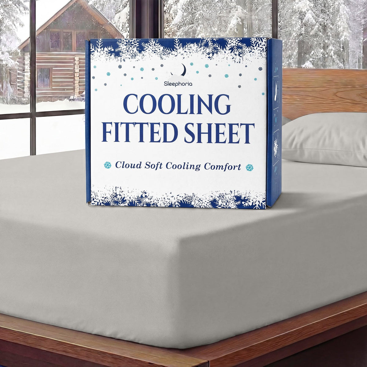 Sleephoria Cooling Fitted Sheet box standing on a light gray fitted sheet, with matching pillows and snowy trees outside.