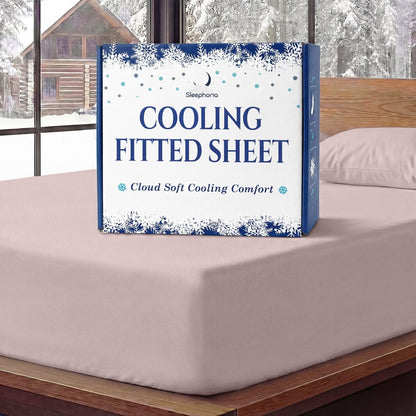 Sleephoria Cooling Fitted Sheet box standing on a blush pink fitted sheet, with matching pillows and snowy trees outside.