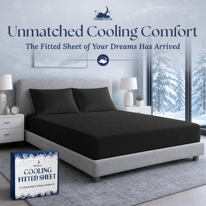 Black fitted sheet pulled over a mattress with two matching pillows on a gray bed, beside Sleephoria packaging.
