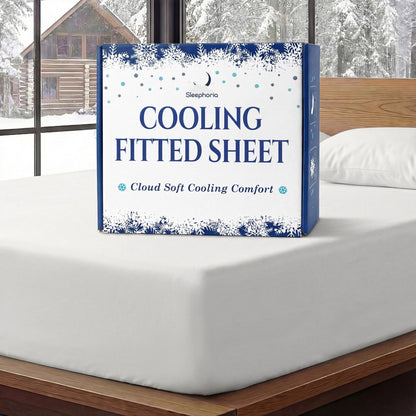 Sleephoria Cooling Fitted Sheet box standing on a white fitted sheet, with matching pillows and snowy trees outside.
