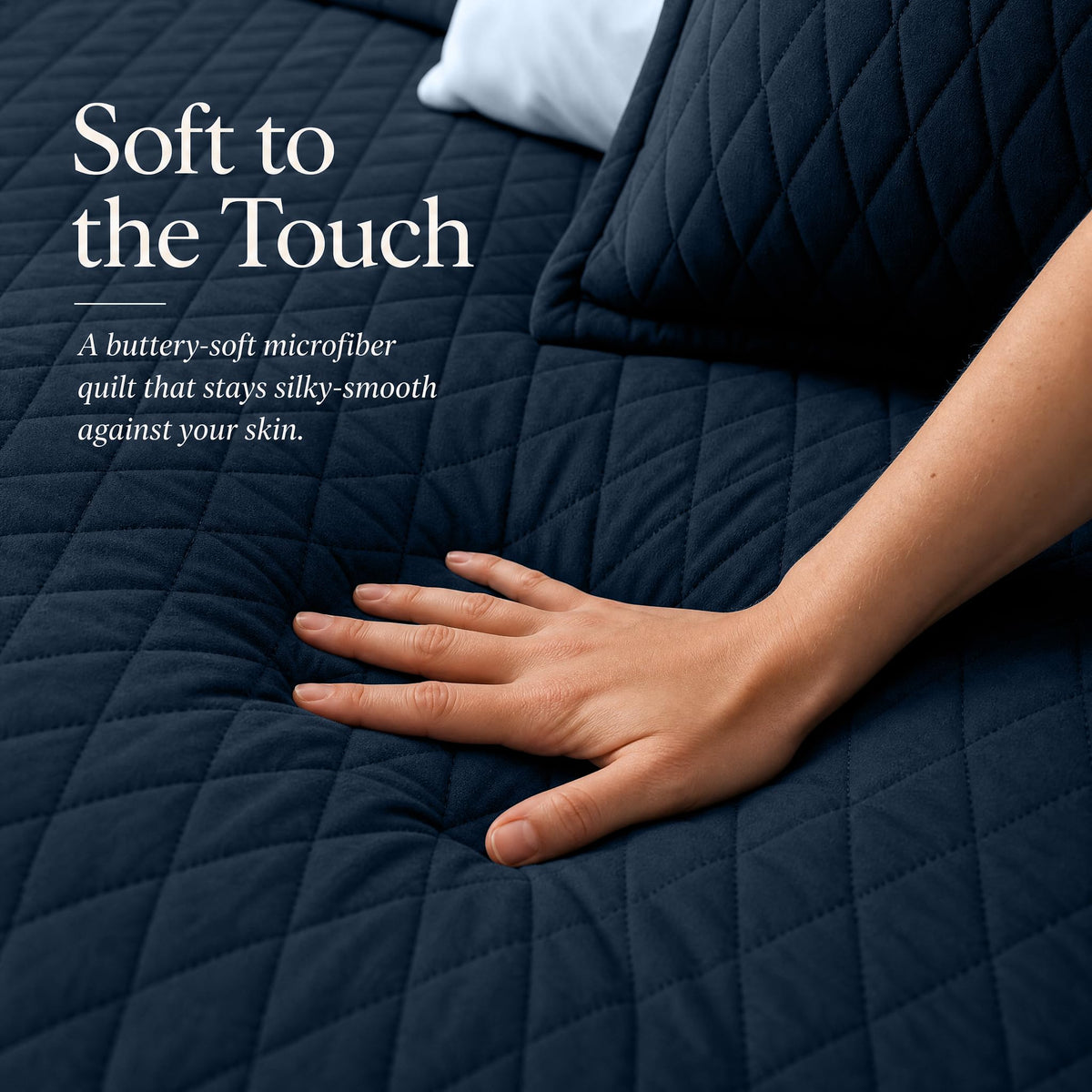Hand touching a navy blue diamond stitched quilt beside matching shams beneath "Soft to the Touch".