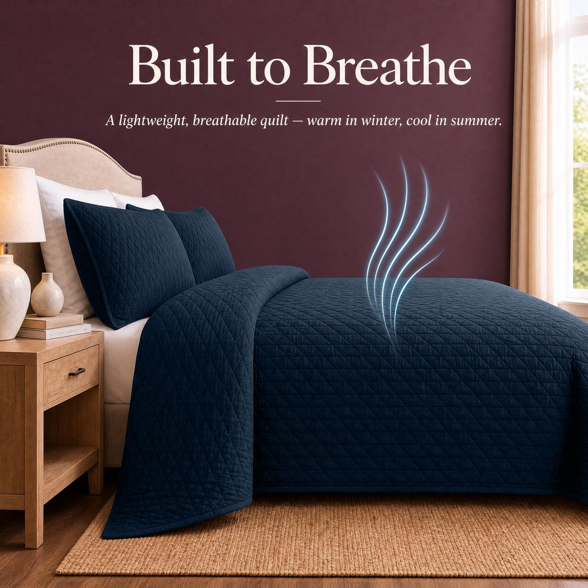 Navy blue quilt and shams on a bed with blue airflow lines above the cover beneath "Built to Breathe".