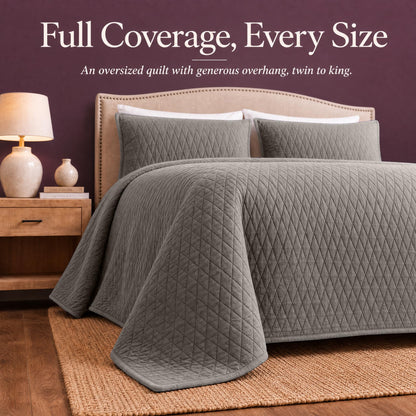 Taupe diamond quilt draped over both sides and the foot of a bed with matching shams beneath "Full Coverage, Every Size".