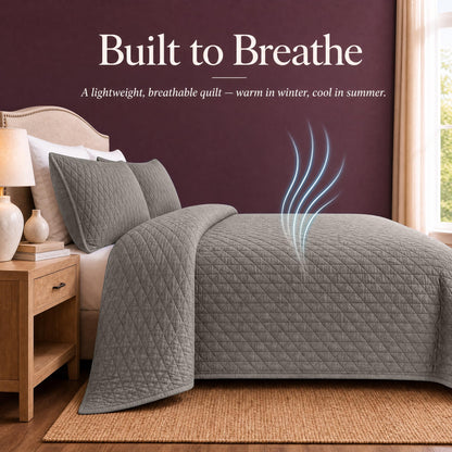 Taupe quilt and shams on a bed with blue airflow lines above the cover beneath "Built to Breathe".