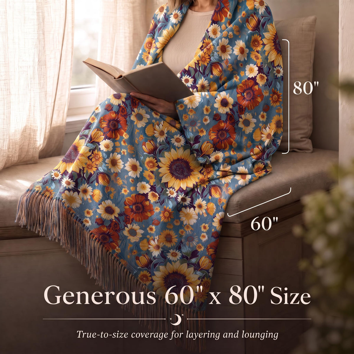 Person reading while wrapped in a blue and yellow small floral fringed throw, with size arrows labeled 60 by 80 inches.