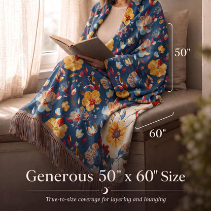 Person reading while wrapped in a blue with large red and yellow flowers fringed throw, with size arrows labeled 50 by 60 inches.