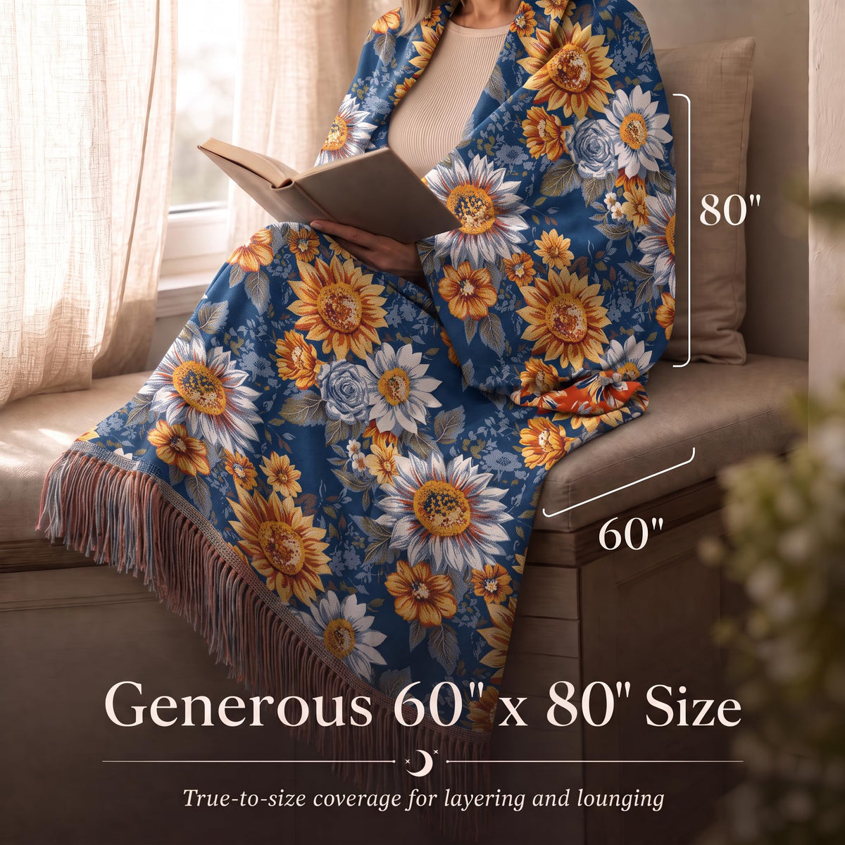 Person reading while wrapped in a blue and orange sunflower patterned fringed throw, with size arrows labeled 60 by 80 inches.